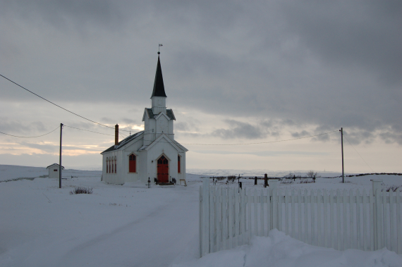 Bilde av en hvitkirke i vinterlige omgivelser.